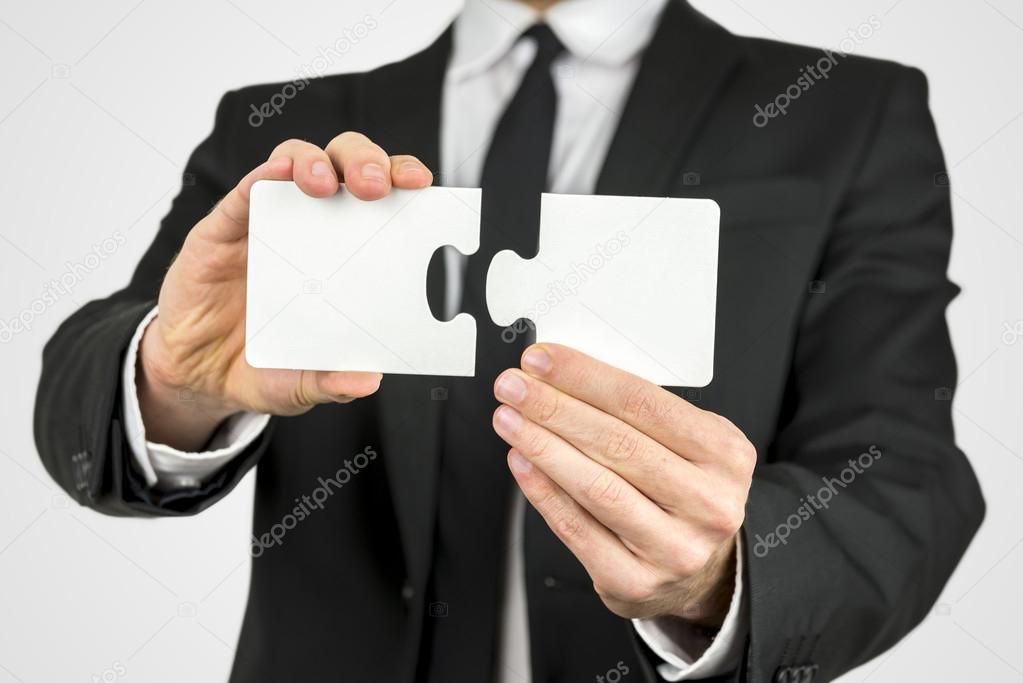 Businessman holding two puzzle pieces