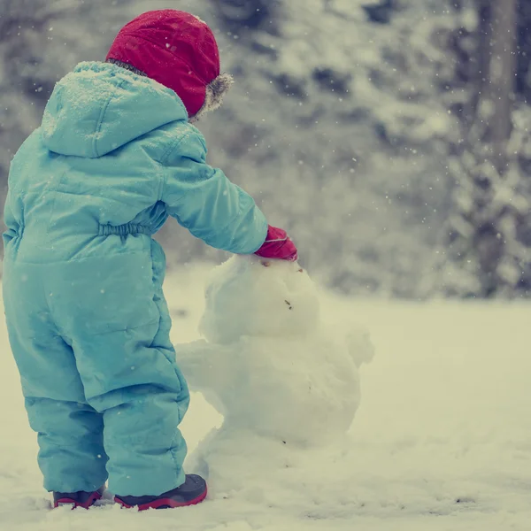 Kleinkind baut einen Schneemann — Stockfoto