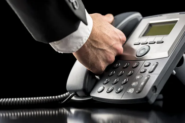 Uomo d'affari che fa una chiamata su un telefono fisso — Foto Stock