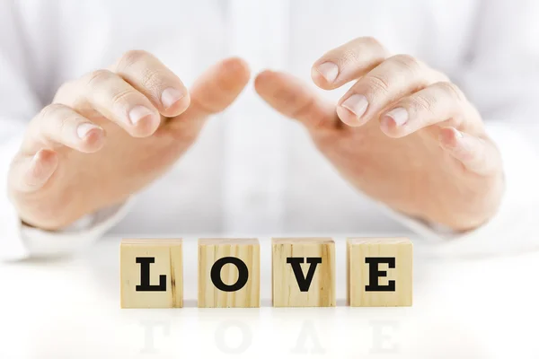 Man med skyddande händer över ordet kärlek — Stockfoto