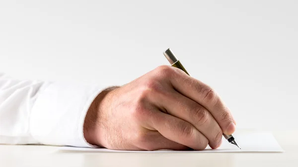 Homme écrivant sur une feuille de papier avec un stylo plume — Photo