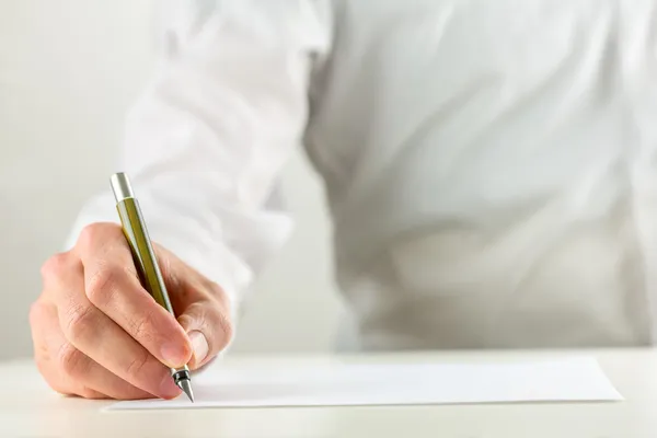 Homem escrevendo com uma caneta-tinteiro em papel em branco Fotografia De Stock