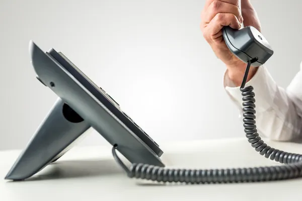 Telefone com o receptor segurado por uma mão masculina — Fotografia de Stock