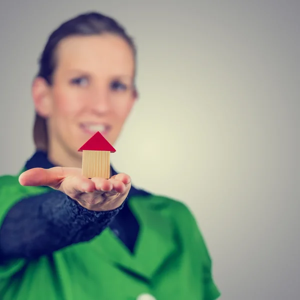 Female real estate agent holding out a model house — Stock Photo, Image