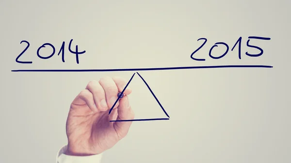 Man balancing 2014 and 2015 on a seesaw — Stock Photo, Image