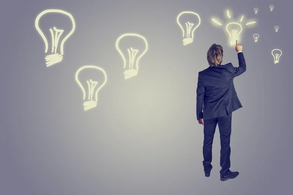 Businessman drawing light bulbs in the air — Stock Photo, Image