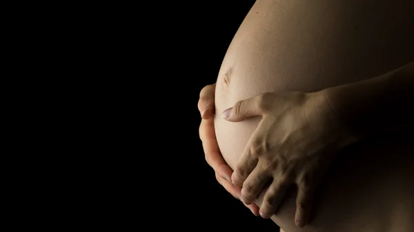 Mulher embalando sua barriga grávida em suas mãos — Fotografia de Stock