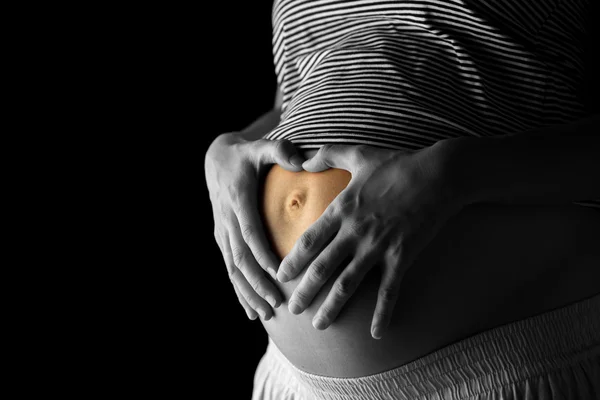 Беременная женщина делает сердечный жест на животе — стоковое фото