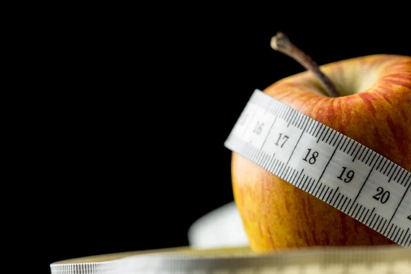 Fresh tasty apple wrapped with a measuring tape — Stock Photo, Image
