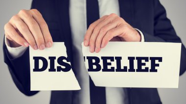 Man holding torn paper with the words Dis-Belief clipart