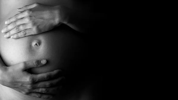 Expectant mother holding her belly, in low-key — Stock Photo, Image