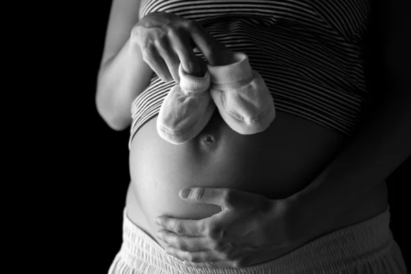 Zwangere vrouw met een paar van baby slofjes — Stockfoto
