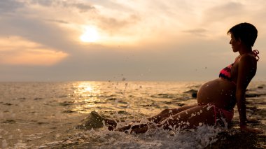 sığ sularda oturan hamile kadın