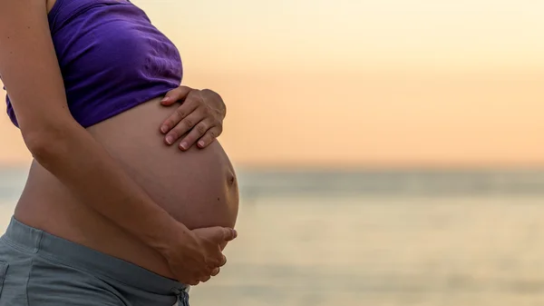 Těhotná žena kolébání její břicho s rukama — Stock fotografie