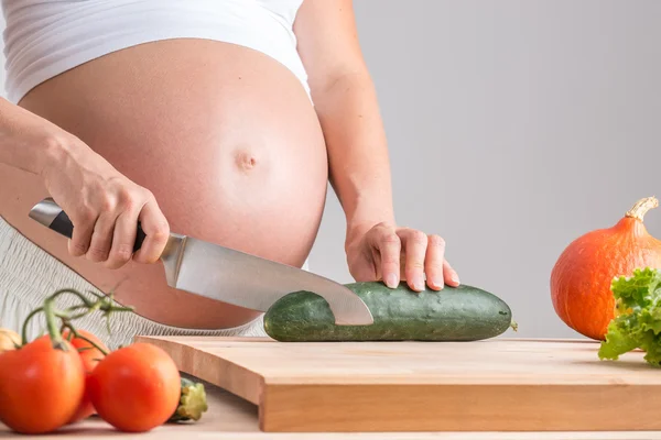 Mulher grávida cortando legumes frescos — Fotografia de Stock