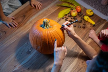 Nerede keseceklerini belirlemek için Cadılar Bayramı balkabağı çizen bir anne ve çocuğunun en iyi görüntüsü..
