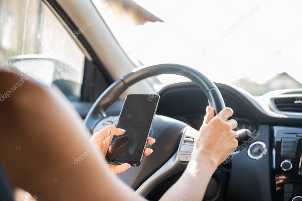 Woman using her mobile phone and texting while driving a car.