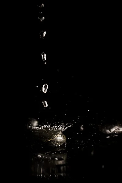 Water droplets splashing onto a black surface — Stock Photo, Image