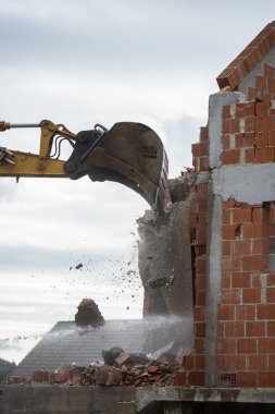 Mechanical digger demolishing a building clipart