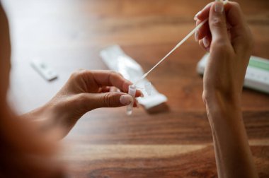 Küresel bir koronavirüs pandemik görüntüsünde test çözeltisi içinde covid19 öz test çubuğunu batırıyorum..