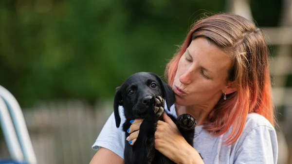 Young Woman Cuddling Her Cute Little Black Labrador Puppy — Stock Photo, Image