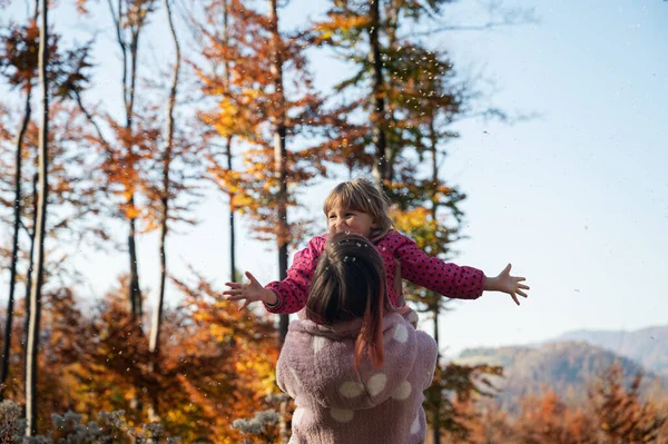 若いですお母さん持ち上げる彼女の笑顔幼児娘でザ空気外で美しい秋の自然 — ストック写真