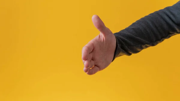 Mężczyzna Ręka Oferuje Uścisk Dłoni Żółtym Tle — Zdjęcie stockowe
