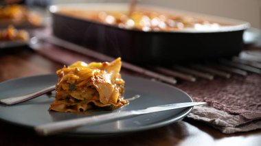 Lezzetli, sulu bir parça vejetaryen lazanyası evcil mutfak masasında servis ediliyor..