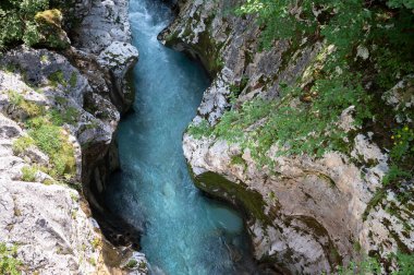 Güneşli bir yaz gününde Soca Nehri 'nin en tepedeki manzarası büyük vadi kayalarının arasından hızla akıyor..