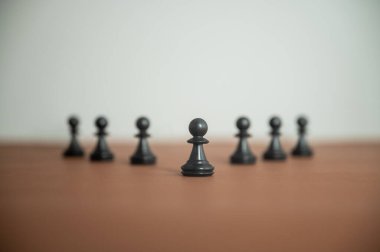 Low angle view of chess pawn figures placed in a pyramid shaped line on brown surface in a conceptual image of power and teamwork. 