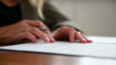 Video of a caucasian woman signing a document or contract and closing the folder afterwards.