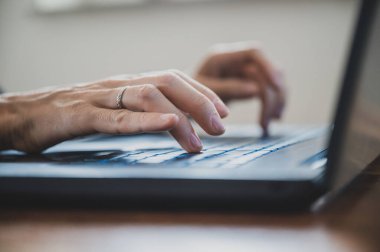 Low angle closeup view of female hands using laptop computer.
