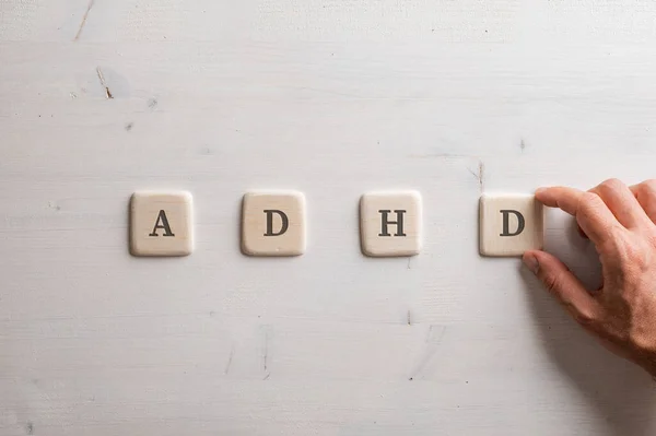 Male Hand Assembling Adhd Sign Spelled Four Wooden Cut Squares — Stok fotoğraf