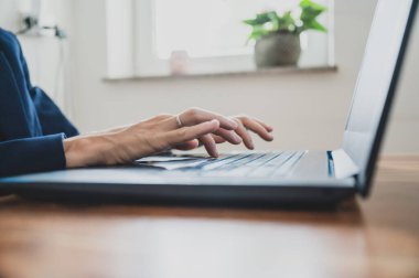 Ofis masasında klavyede dizüstü bilgisayar kullanarak çalışan bir iş kadını ya da sekreterin düşük açılı görüntüsü.
