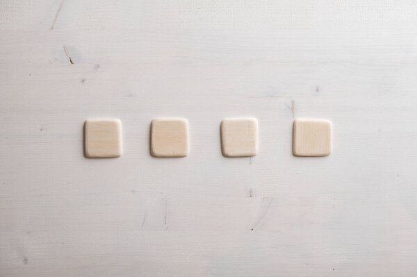 Four blank wooden squares placed in a row over wooden background.