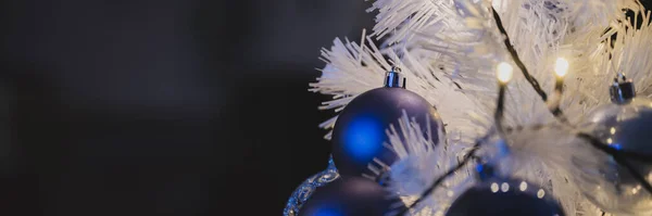 ライト付きの白いクリスマスツリーにぶら下がっている光沢のある青い休日の泡のワイドビュー画像 コピースペース付き — ストック写真