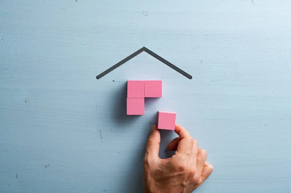 Mão Masculina Montando Uma Casa Feita Blocos Madeira Rosa Sobre — Fotografia de Stock