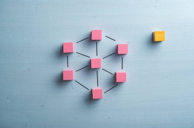 Hayali çizgilerle bağlanmış pembe tahta bloklardan oluşan bir ağ ve onların yanına yerleştirilmiş bir yabancı gibi boş bir blok. Pastel mavi ahşap arka planda.