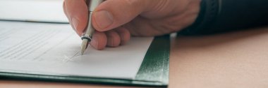 Düşük açılı, yakın plan, beyaz bir erkeğin bir belgeyi imzalarken ya da mürekkep kalemiyle kontrat imzalarken. Geniş görünüm resmi.