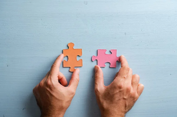 Bovenaanzicht Van Mannelijke Handen Met Twee Overeenkomende Puzzelstukjes Oranje Roze — Stockfoto