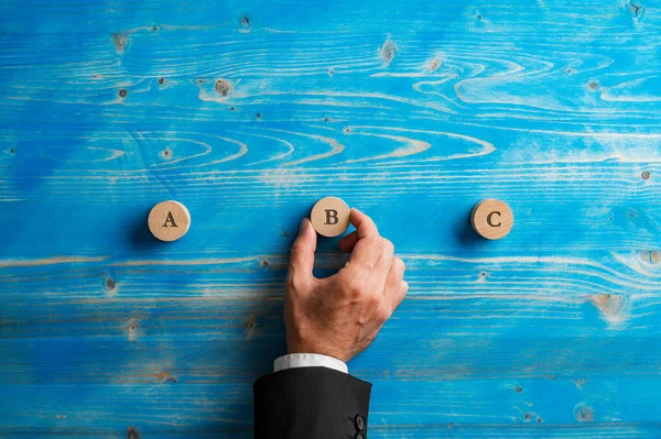 一个商人的手 在蓝色的木制背景上放置有字母A B和C的木制切割圆圈 — 图库照片