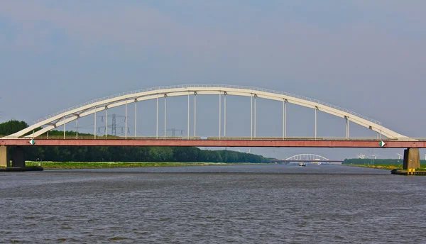 Nykyaikaiset sillat kattavat joen Hollannissa Tuuliturbiineilla pitkin pankkia — kuvapankkivalokuva