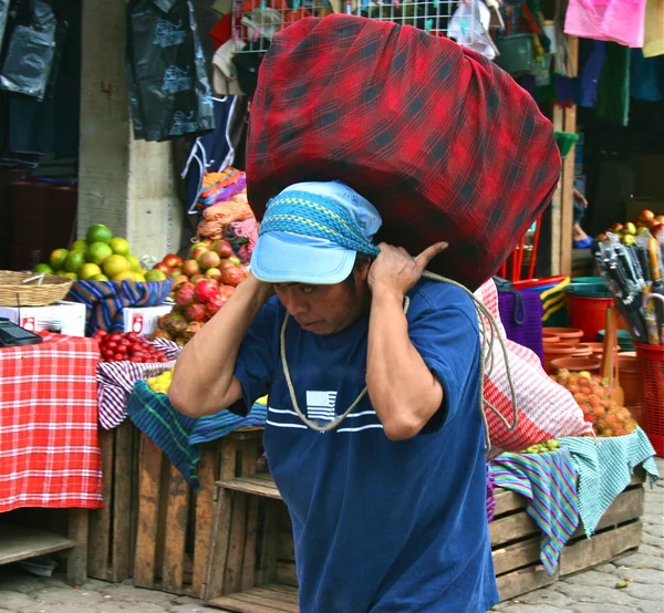 Homem carrega carga pesada no mercado da Guatemala — Fotografia de Stock