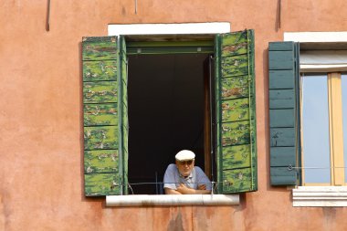 yaşlı adam üst katta bir pencereden izlerken