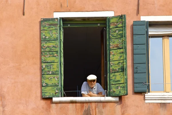 Vanha mies katselee yläkerran ikkunasta — kuvapankkivalokuva
