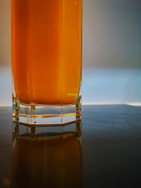 暗誘導部に反射したオレンジジュースの六角形のガラス — ストック写真