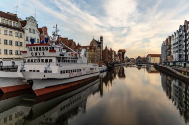 Gdansk, Polonya - 24 Ekim 2020: Motlawa nehri üzerindeki eski şehir binaları sabah yeşil köprüden teknelerle görülüyor