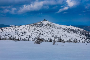 Bulutlu bir sabahta dağların ve tepelerin karlı manzarası