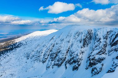 Bulutlu bir sabahta dağların ve tepelerin karlı manzarası
