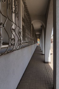 Ön cephesinde büyük kavisler olan yenilenmiş eski binada uzun bir tünel.